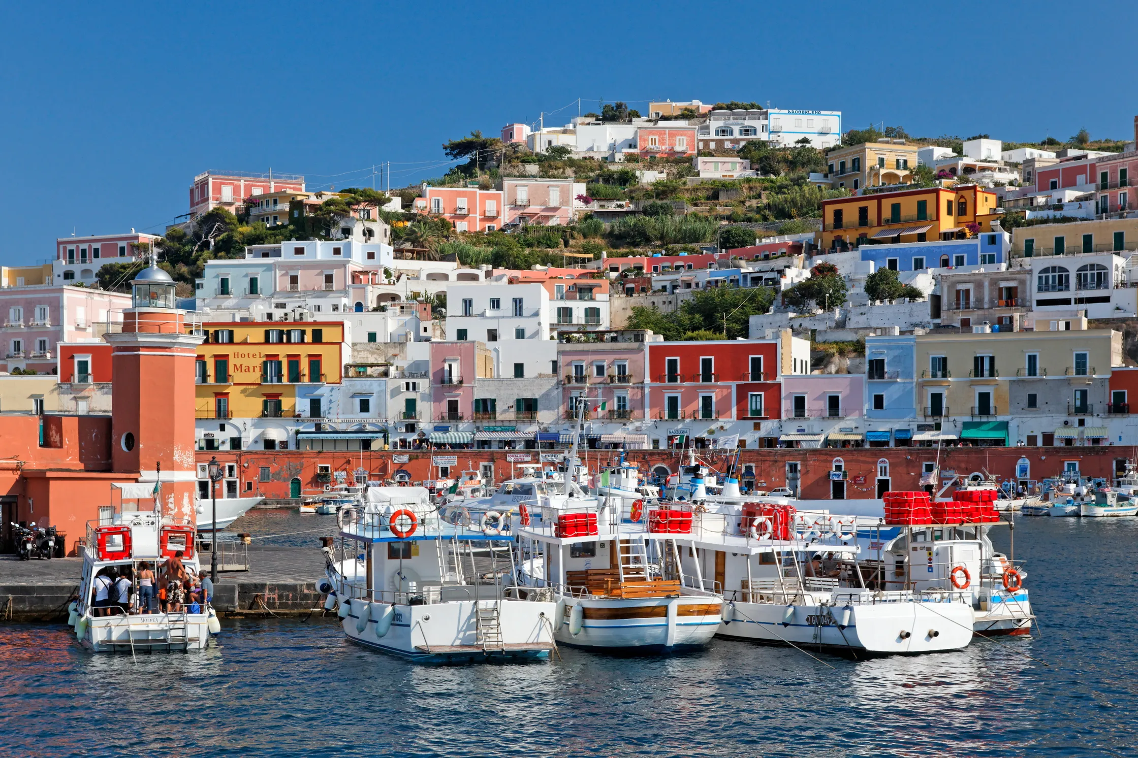 Colorful buildings of Ponza harbor with boats docked in blue waters