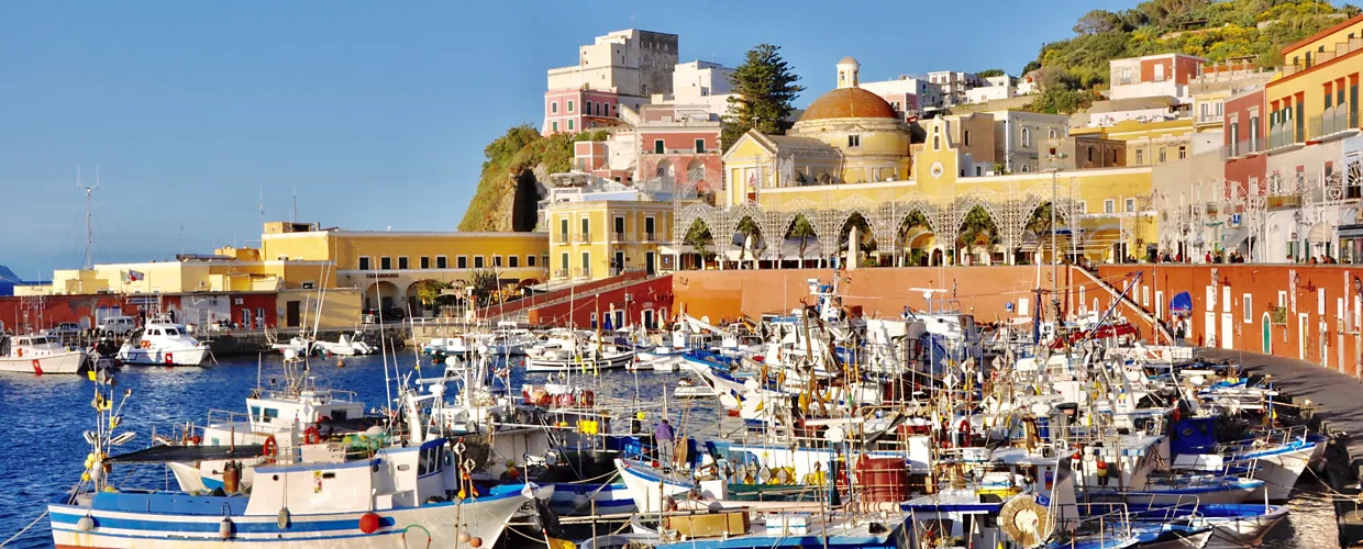 Colorful panoramic view of Ponza's harbor with fishing boats and the town's vibrant buildings rising up the hillside