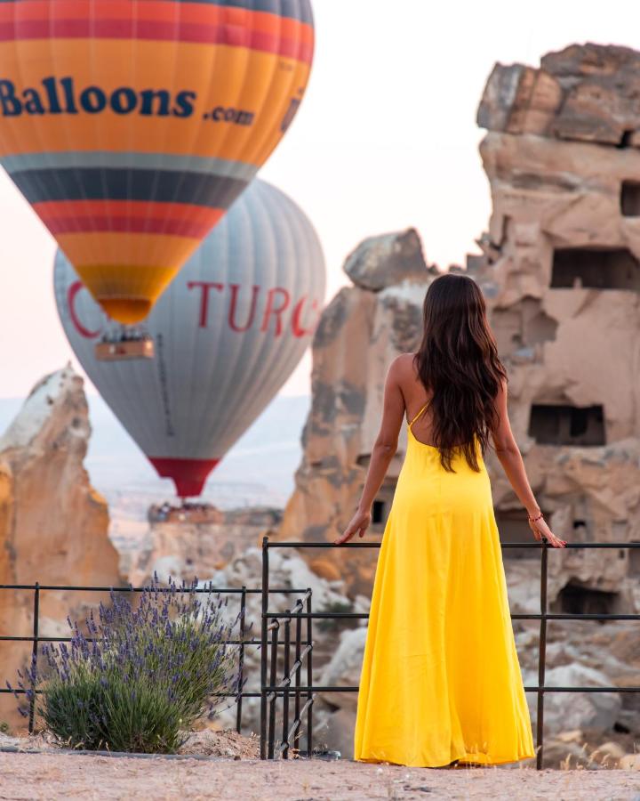 Woman in yellow dress overlooking hot air balloons in Cappadocia