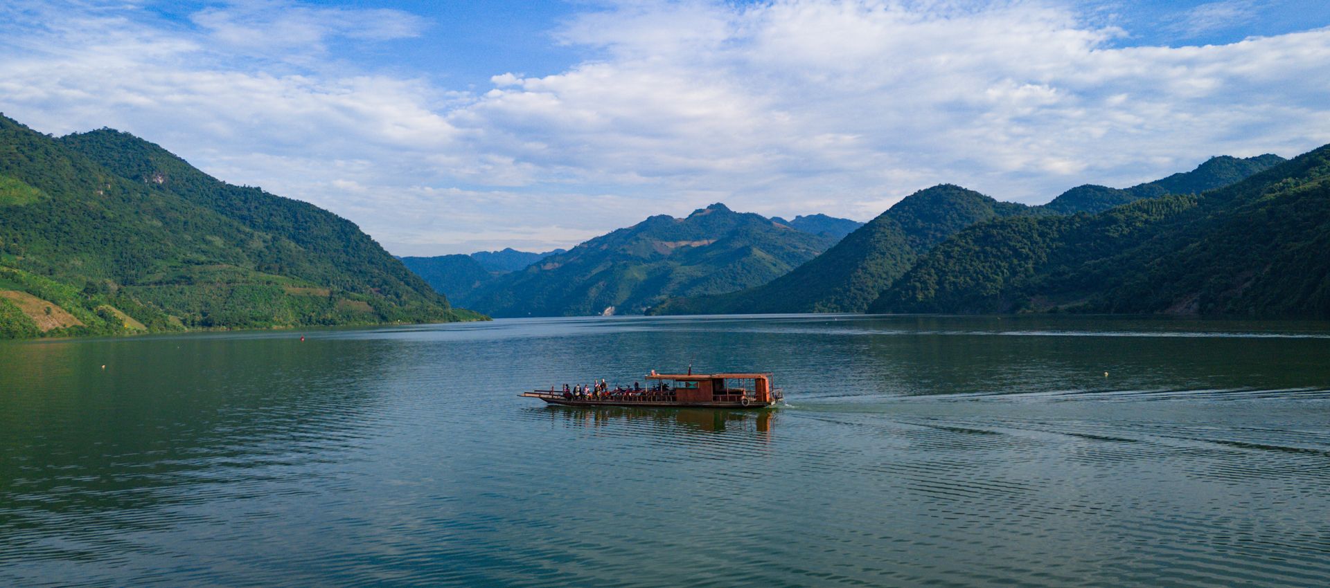 Ferry boat crossing a scenic mountain lake surrounded by lush green mountains