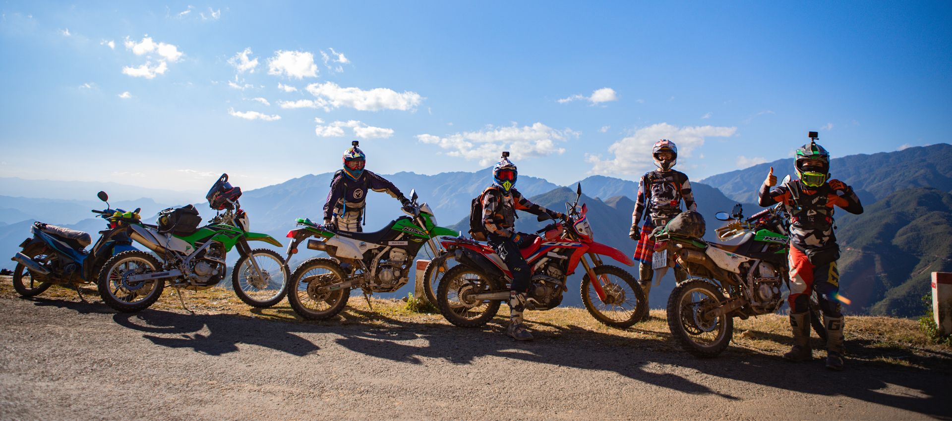 Group of motorcyclists with their dirt bikes overlooking a spectacular mountain vista